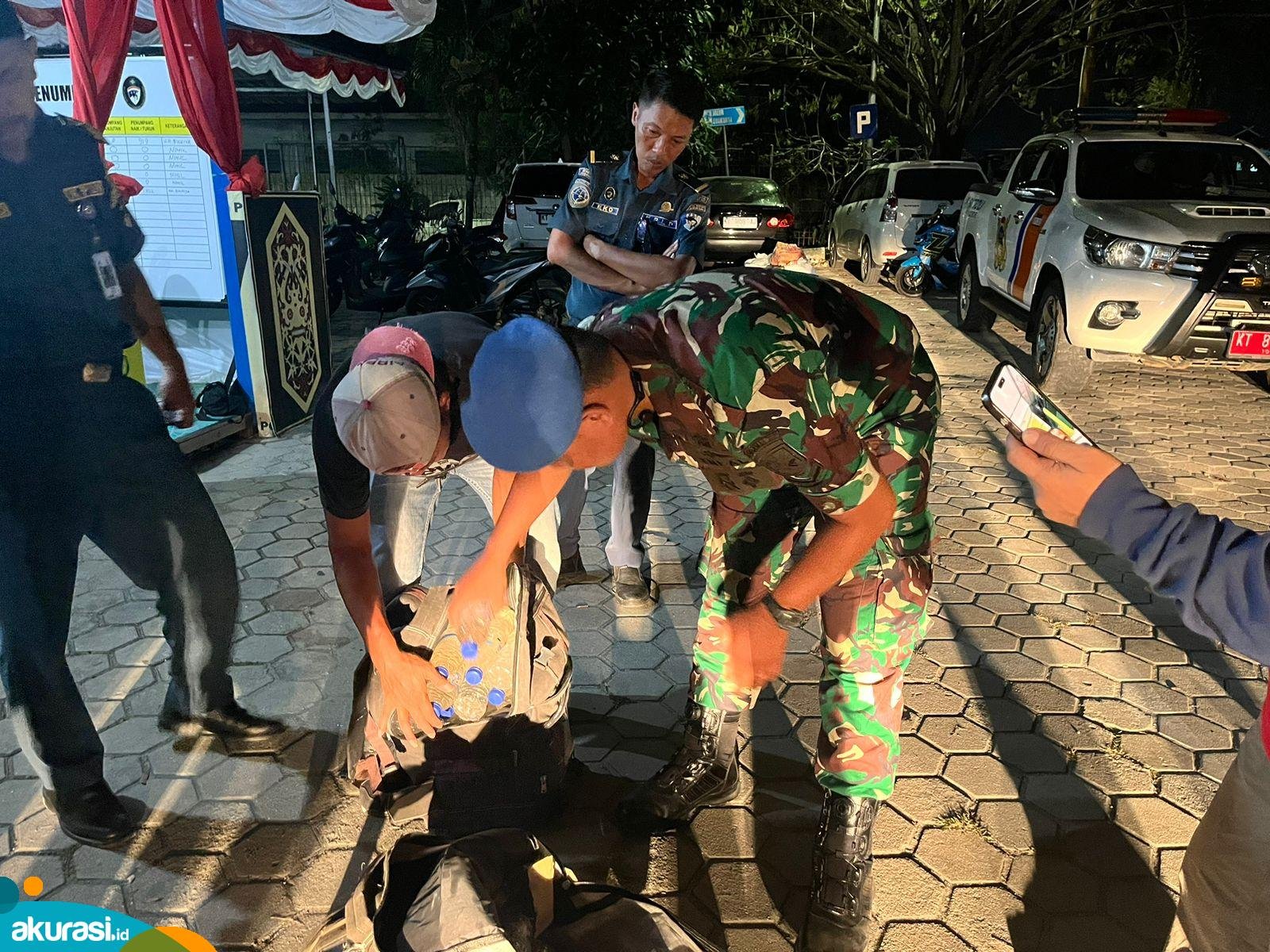 Saat petugas memeriksa dua tas tak bertuan yang ternyata berisi puluhan botol miras ilegal Cap Tikus. (Nugrah/Akurasi.id)