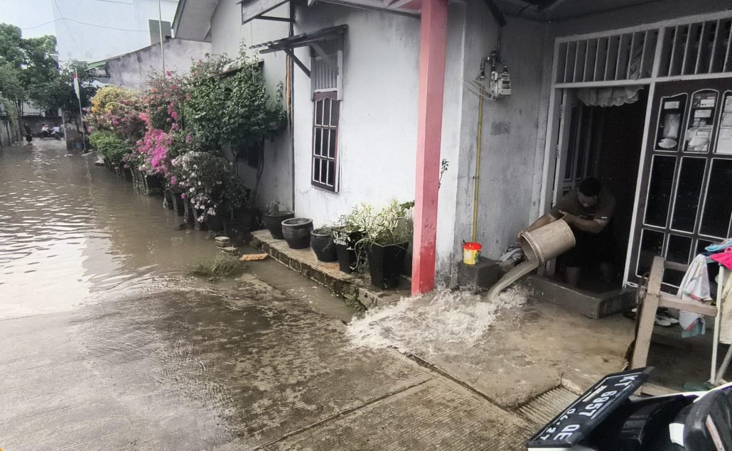 Rumah warga Bontang terendam banjir. Seorang warga sedang menguras air di dalam rumahnya di wilayah RT 27, Kelurahan Bontang Baru. (Dwi Kurniawan Nugroho/Akurasi.id)